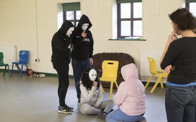 Four young people taking part in a drama session wearing white masks