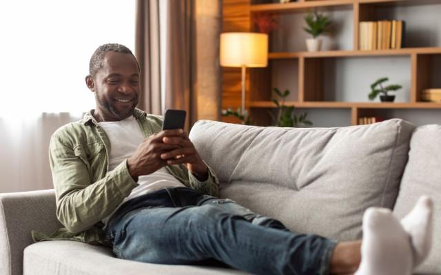 Representing what is a fostering agency - a man relaxing on a sofa with his mobile