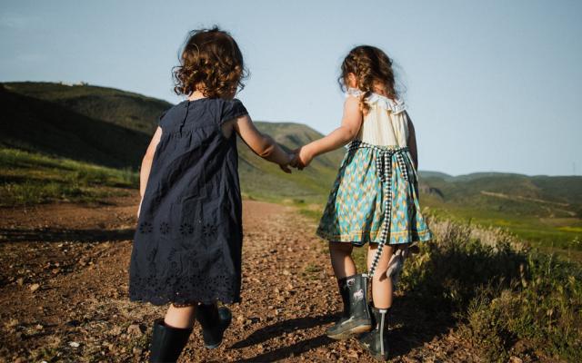 Two children holding hands representing fostering and adoption
