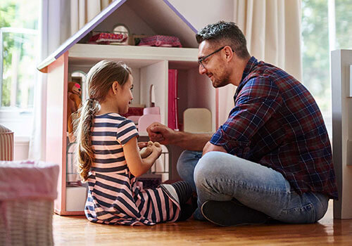 Father and daughter playing with a dolls house