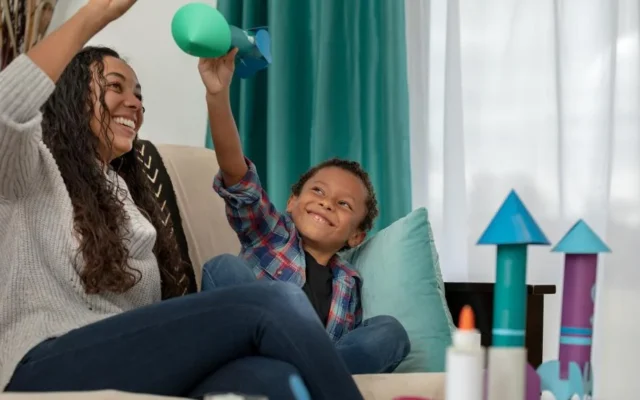 woman and boy playing with paper rockets