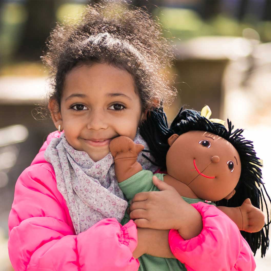 girl in pink coat holding doll