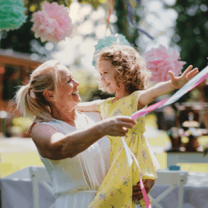 A blond women with a young girl and some ribbon on a sunny day