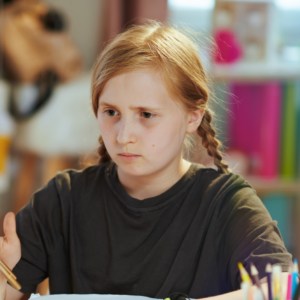 girl sat at desk, writing