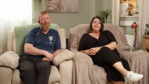 Foster Carers Sam and Mike sat on sofa in their home