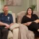 Foster Carers Sam and Mike sat on sofa in their home